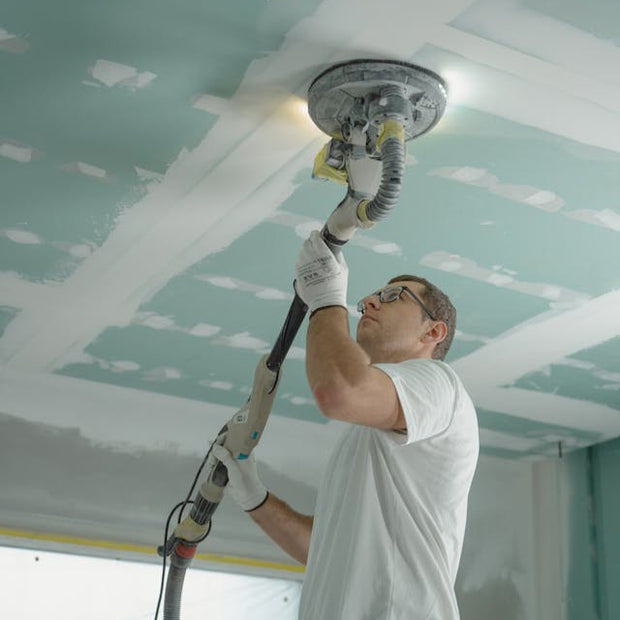 Contractor sanding drywall ceiling during repair project in Colorado