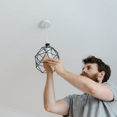 Electrician installing a modern ceiling light fixture during a residential electrical upgrade.