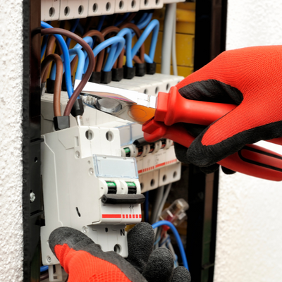 Electrician working on overhead wiring and conduit installation for a commercial building project.
