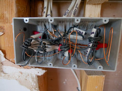 Exposed electrical box showing tangled wires during a home rewiring and repair project.