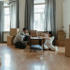 A couple assembling a small table in their new home, surrounded by moving boxes, representing reliable handyman furniture assembly services for families.
