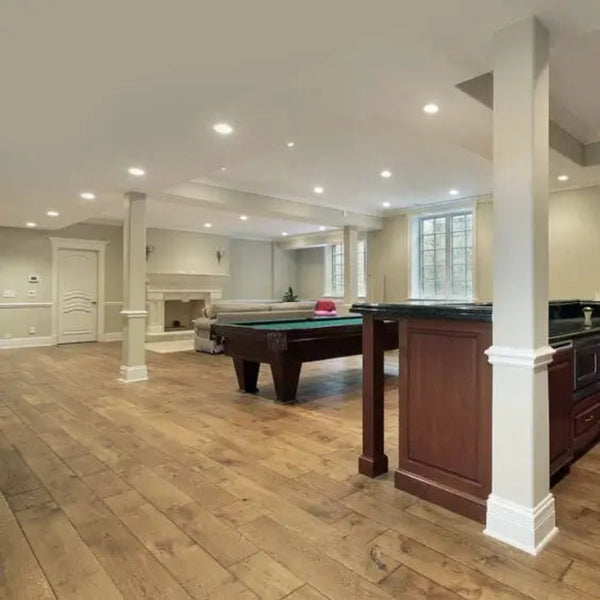 Wood look luxury vinyl plank flooring installed in open basement with kitchen area and finished trim