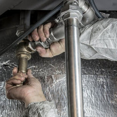 Handyman using a red wrench to repair bathroom sink pipes during a plumbing service call.