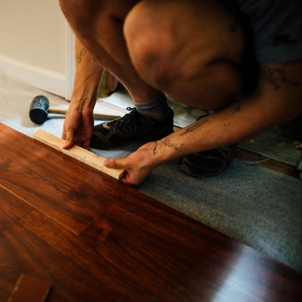 contractor installing engineered hardwood flooring plank and fitting boards during flooring installation in denver colorado