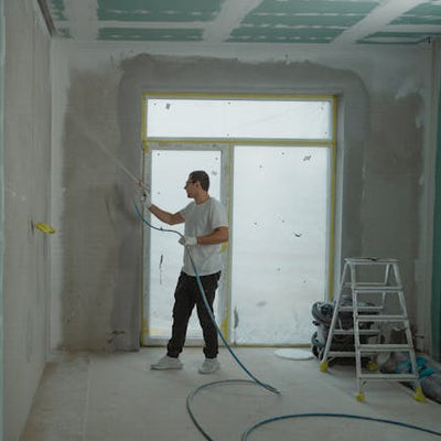 Handyman spraying drywall mud and applying wall texture during interior renovation in Thornton Colorado