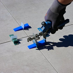 Handyman using tile leveling tool while installing floor tiles during home repair in Thornton Colorado
